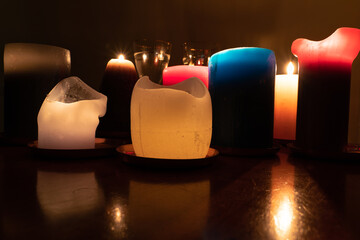 The light candles in the dark is reflected on the table surface and in glass glasses at night in the house