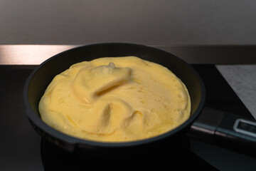 Omelet in a black pan on an induction hob