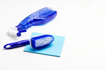 Cleaning products. Spray bottle with blue liquid, brush and sponge on table.