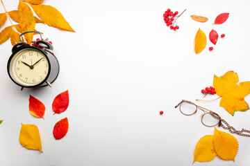 Yellow autumn leaves and an alarm clock on a white background, thematic layout, autumn, it's time to learn