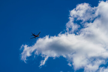 Fototapeta na wymiar Passenger jet plane flying into white cloud on blue sky