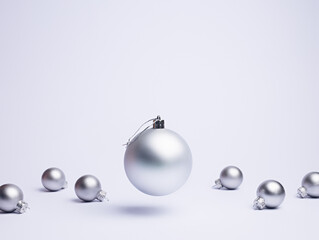 Creative Christmas layout made with flying and levitating bauble ornament with small silver balls on bright white background. Minimal Xmas or New Year celebration concept. Winter festive composition.