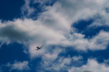 Passenger jet plane flying into white cloud on blue sky