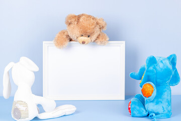 Toys with empty white frame on light blue background. Toy teddy bear and plush stuffed toys and...