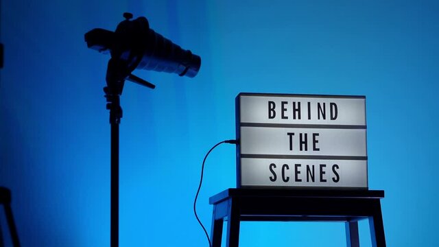 Behind the scene light box. Black text on white lightbox of word Behind the scenes. prop include megaphone movie clapperboard and director chair in studio. footage for video production making of.