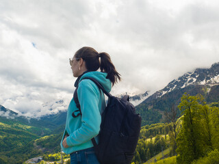Young female tourist with a backpack on her back hiking in the mountains,