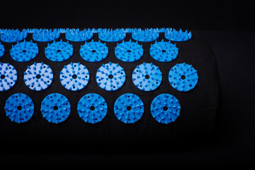 Acupuncture blue mat with many plastic spikes on black background. Alternative therapy and...