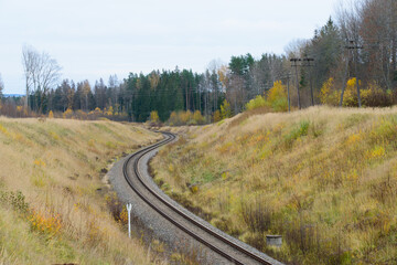 A winding railway track that leads through a mountain valley inside the forest in autumn
