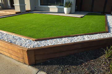 Artificial grass lawn turf with wooden edging in the front yard of a modern Australian home or residential house. - obrazy, fototapety, plakaty