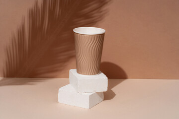 Podium made of natural stone with the shadow of tropical leaves in the background, paper cups. Beautiful background from natural materials.