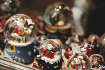 Stylish christmas snow globes in window shop. Christmas festive street decor in european city...