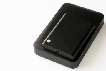 Comparison of sizes of external SSD and external 2.5-inch HDD. Computer digital peripherals. Data storage on external drives. Free space for an inscription. Selective focusing.