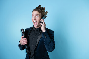 shocked businessman with a crown on his head uses a laptop and a phone.