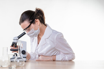 lab technician looks into the eyepiece of a microscope, a young female doctor