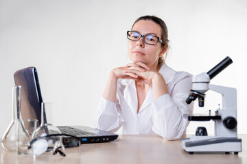 young woman, a laboratory assistant or a researcher is working at a laptop in the laboratory