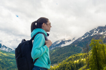Young female tourist with a backpack on her back hiking in the mountains,