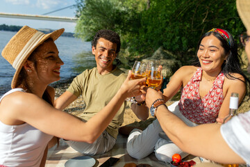 A group of diverse friends enjoys music and food on the beach. Picnic time.