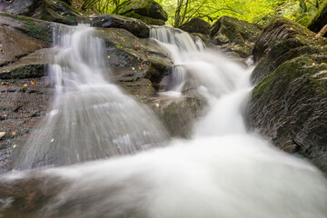 Obraz premium Long exposure of a waterfall on the Hoar Oak Water river at Watersmeet in Exmoor National Park