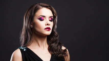 Fototapeta premium Gorgeous young brunette in a chic evening look. Scarlet lips and eye shadow, wave hair styling
