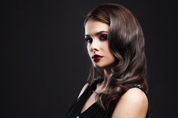 Gorgeous young brunette in a chic evening look. Scarlet lips and eye shadow, wave hair styling