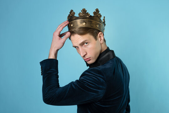 Career ambitions, concept. A young man in a suit puts a crown on his head,
