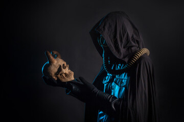 Post-apocalyptic world, concept. A gloomy servant of the devil cult in a black hood