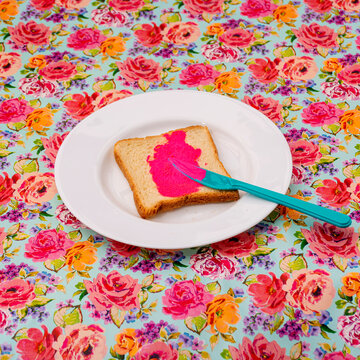 Pink flourescent spread on toast with a flowery background. Retro concept.