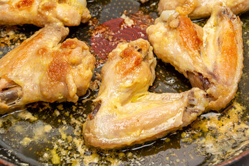 Close Up chicken legs and chicken wings are fried in a pan with sauce