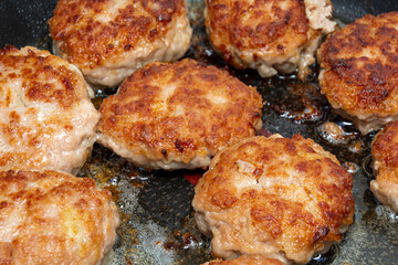 Minced meat cutlets are fried in a frying pan. Food background, close-up, top view.