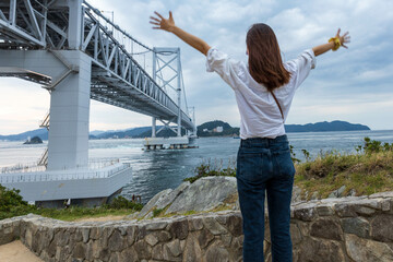 Young woman with arms spread enjoying view of suspension bridge