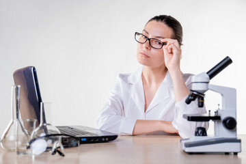 young woman, a laboratory assistant or a researcher is working at a laptop in the laboratory