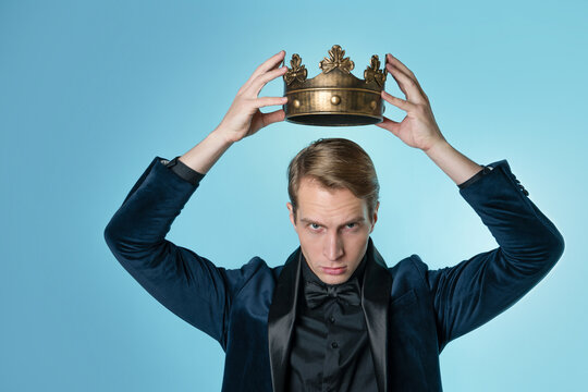 Career ambitions, concept. A young man in a suit puts a crown on his head,