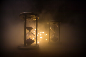 Time concept. Silhouette of Hourglass clock and old vintage wood clock with arrow and smoke on dark...