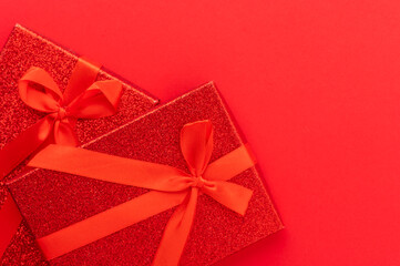 Beautifully packaged gifts of red color on a red background. Minimalism. There are no people in the photo. Christmas, New Year, wedding, wedding, discounts, sales, family holidays and celebrations.