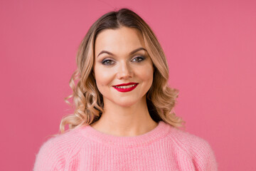 Fototapeta premium Young attractive woman in a warm pink sweater on a pink background,