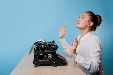 young woman writer at a typewriter, is inspired, is passionate about writing a text.