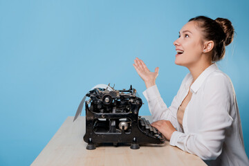 happy young woman is an author at a typewriter, is inspired,