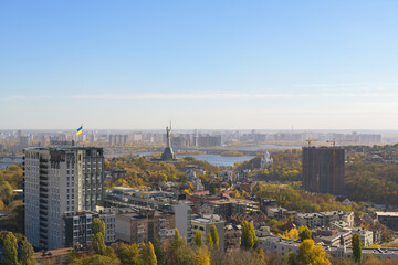Beautiful panorama of autumn Kiev. View from the left bank to the Dnieper. Wide river in the city and autumn yellow trees.Village and city