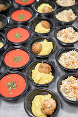 Food delivery. Different in plastic disposable lunch box with healthy natural food. Chicken broth, mashed soup, mashed potatoes with cutlet, seafood pasta, salads, pilaf with a fresh bun.
