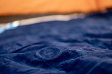 Selective focus of an inflatable air mattress on the floor of a tent being filled up. 