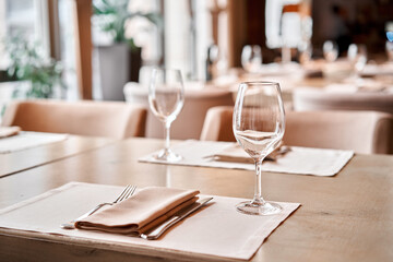 Wine glasses in the foreground. The chairs and table for guests, served with cutlery and crockery
