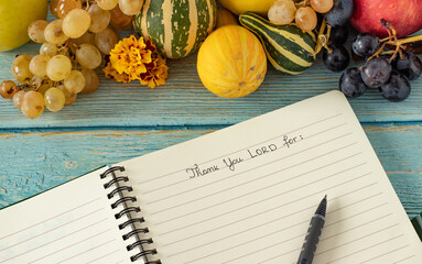 A handwritten text in an open notebook. Thank You, LORD. Fall fruits on wood table. The biblical...