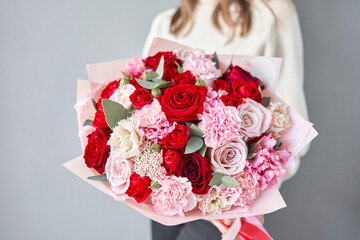 European floral shop. Red and pink Beautiful bouquet of mixed flowers in womans hands. the work of the florist at a flower shop. Delivery fresh cut flower. - 464916212