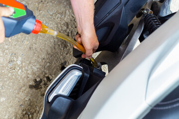 Repair and maintenance of motorcycles. A car mechanic pours engine oil into a motorbike engine