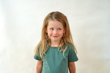portrait of a happy child on a white background in a green t-shirt smiling. The little girl plays...