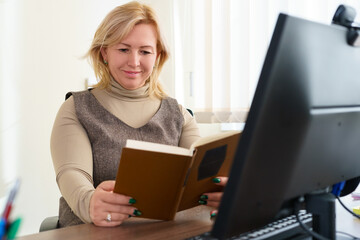 Mature woman reading book at the office. Knowledge Relax Concept