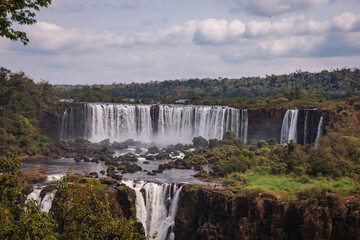 Obraz premium a waterfall in the middle of the forest with blue sky in the background.