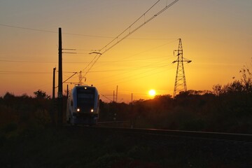 Fototapeta na wymiar silhouette of a railcar and electric railroad traction on a sunset background 