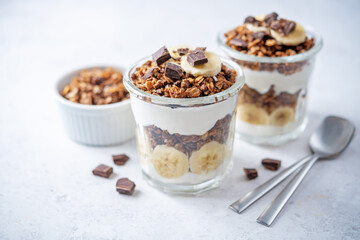 Chocolate and banana Greek yogurt granola parfait in a glass