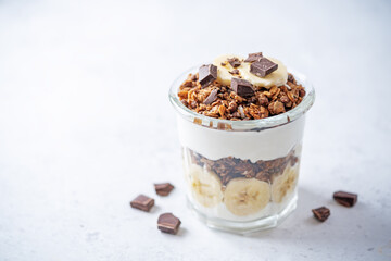 Chocolate and banana Greek yogurt granola parfait in a glass